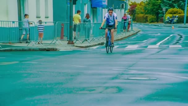 青い服と青い自転車を着たレーサーが寒い日に自転車で通りを走っています — ストック動画