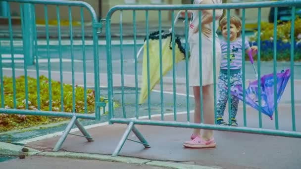 Δύο Μικρά Παιδιά Ομπρέλες Στέκονται Πίσω Από Φράχτη — Αρχείο Βίντεο