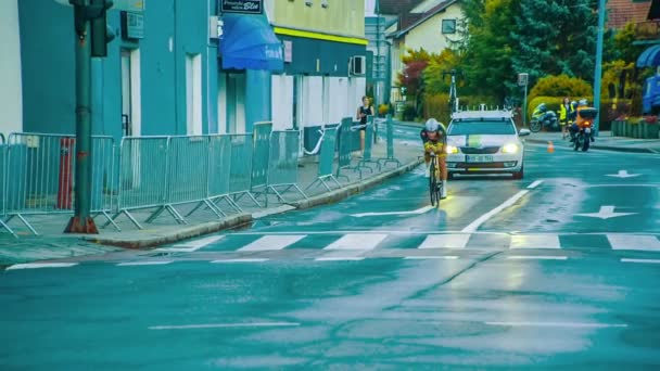 白い車がロードバイクレーサーに付き添っている 昨日の夜雨が降っている — ストック動画