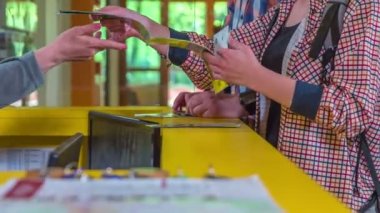 Genç bir kadın haritayı açıyor ve tezgahtaki genç bayana bir şey soruyor..