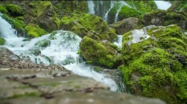 Şelaleden gelen suyun kendi akıntısı vardır ve kayaların üzerinden huzur içinde akar. Kayalar yosunla kaplı..