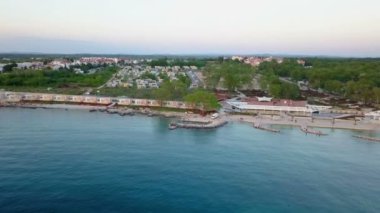 Güzel mavi bir deniz ve arka planda evleri olan bir köy. Hava görüntüsü.