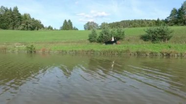 Genç bir gelin, gölün etrafında dolaşırken klasik bir arabanın içinde dikiliyor ve etrafına bakıyor. Hava görüntüsü.