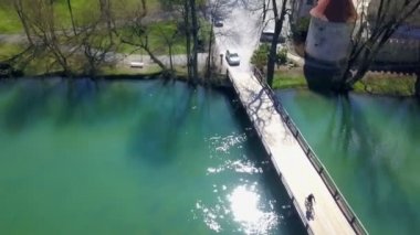 Genç çekici bir adam bisiklet sürüyor, trafik dolu bir köprüden geçiyor.