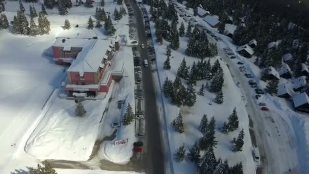 我们可以看到一个在滑雪胜地有度假别墅的村庄 空中射击 也有很多车停在路边 — 图库视频影像