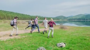 Beş arkadaştan oluşan bir grup sırt çantalarını havaya fırlatıyor ve göle doğru koşuyorlar. Mutlu ve neşeli görünüyorlar..