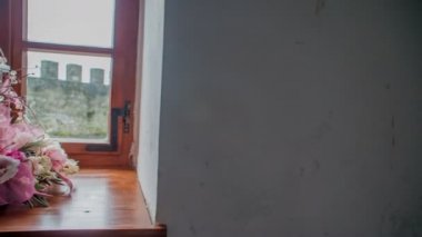 Pencere camında güzel bir buket çiçek duruyor. Güneş bir pencereden parlıyor..