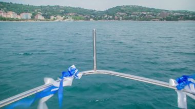 İki beyaz ve mavi kurdele yatın koruma çitine bağlı. Yat, üzerinde gerçekleşmekte olan düğün töreni nedeniyle dekore edildi..