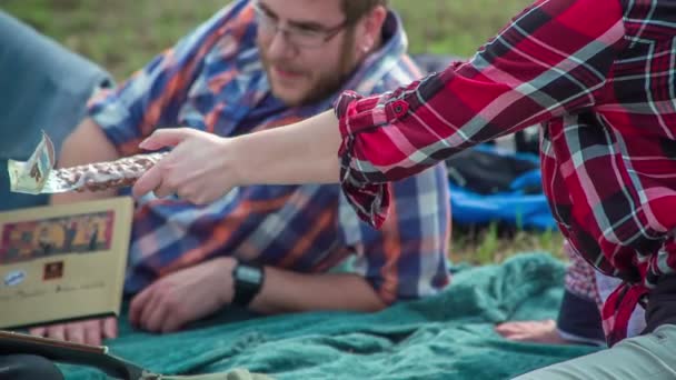 年轻人吃坚果和巧克力 坐在美丽的大自然中间的毛毯上 — 图库视频影像
