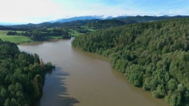 Doğanın ortasında büyük bir göl görebiliriz. Manzara çok güzel yeşil. Hava görüntüsü. Arka planda dağlar var..
