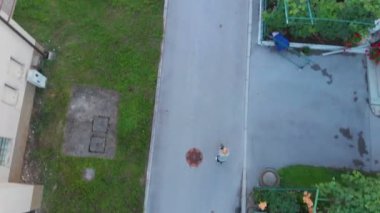 Birileri bir köyün ortasında sokakta scooter 'a biniyor. Hava görüntüsü.