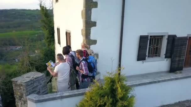 観光客は地図を見ていて 自然を観察しています バックパックを持っている人もいます 城の壁のそばに立っている — ストック動画