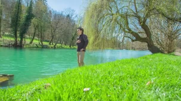 城の近くの公園で池を見ている若者の映像です — ストック動画
