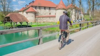 Kalenin yakınındaki köprüde bisiklet süren genç bir adamın görüntüleri.