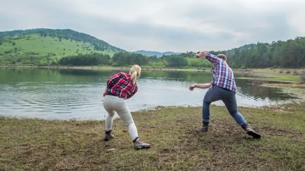 两个朋友在往水里扔石头 他们玩得很开心 — 图库视频影像