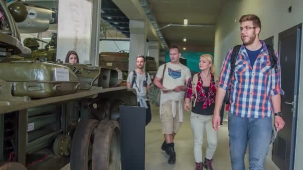 若い人たちが博物館を歩いていて 古いタンクの周りに集まっています — ストック動画