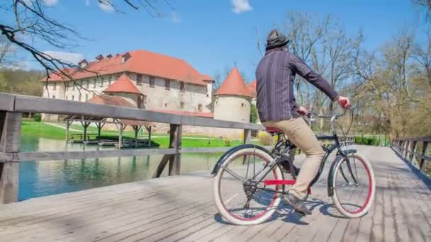 城の近くの橋の上で自転車に乗っている若者の映像 — ストック動画