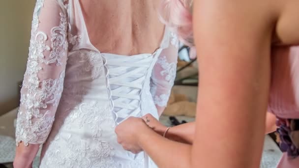 Bridesmaid Helping Bride Tie Her Wedding Dress Back — Stock Video