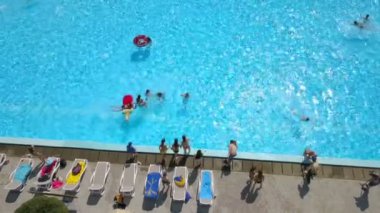 DOMZALE, SLOVENIA - 20. HAZİRAN 2015 Üç kız yüzme havuzuna atlarken el ele tutuşuyorlar. Hava görüntüsü. Güzel bir yaz günü ve insanlar günlerini havuz başında dinlenerek geçiriyorlar..