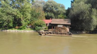 Güneşli bir günde nehirdeki eski su değirmeninin hava görüntüleri.