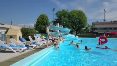 DOMZALE, SLOVENIA - 20. HAZİRAN 2015 Kızlar havuzdan çıkmaya çalışıyor ve bir oğlan havuzun kenarında duruyor..