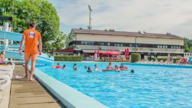 DOMZALE, SLOVENIA - 20. HAZİRAN 2015 Cankurtaran yüzme havuzunda bir aşağı bir yukarı yürüyor ve yüzücülerin güvende olduğundan emin oluyor..