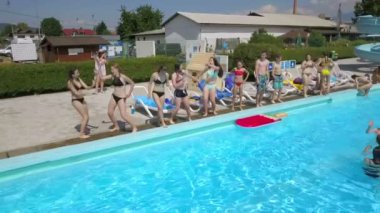 DOMZALE, SLOVENIA - 20. Haziran 2015 Mutlu gençler havuz kenarında zıplayıp dans ediyorlar. Sıcak bir yaz günü ve hava yüzmek için mükemmel..