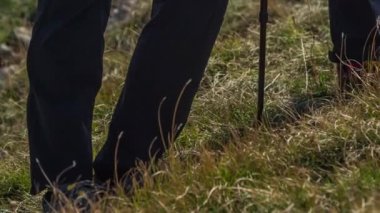 Yürüyüşçüler yürüyüşün ortasında duruyorlar ve manzarayı izliyorlar. Yürüyüşün bu kısmında yürüdükleri çimenleri görebiliyoruz..