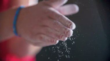 Ellerinde tebeşir var. Bir çocuk spor salonundaki tırmanma duvarına tırmanmaya başlayacak..