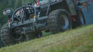 Traktör çim tarlasında sürmeye başlar ve döner tırmıklar samanları yığınlara ayırmaya başlar..