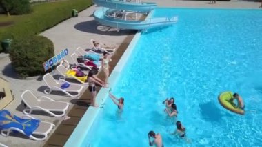 DOMZALE, SLOVENIA - 20. Haziran 2015. Bir kız arkadaşının havuzdan çıkmasına yardım ediyor. Hava görüntüsü. Sıcak bir yaz günü..