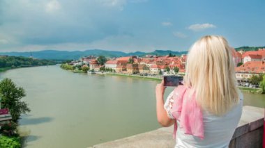 Genç bir kadın güzel bir yaz gününde güzel bir şehrin fotoğraflarını çekiyor..