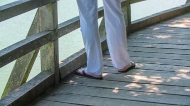 Genç bir adam beyaz yaz kıyafetleri ve parmak arası terlikler giyiyor ve göl kenarında kız arkadaşını bekliyor. Yaz zamanı..