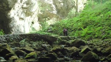 İki insan güzel, yeşil bir doğa içinde yürüyüş yapıyor. Ayrıca bir sürü taş var..