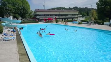 DOMZALE, SLOVENIA - 20. Haziran 2015 'te bir öğrenci havuzun kenarında duruyor ve bazı hareketler ve egzersizler gösteriyor. Diğer öğrenciler onu takip ediyor. Hava görüntüsü.