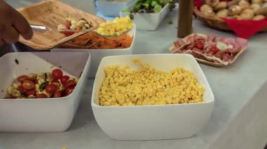 Misafirlerden biri tabağına mısır salatası koyuyor..