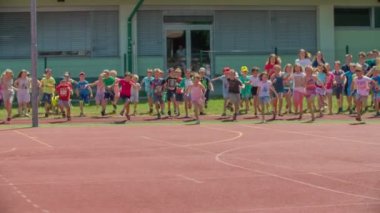 GRIZE, SLOVENIA - 10. Haziran 2017. Okulun dışındaki çimlerin üzerinde duran küçük çocuklar ve herkes spor tesisine doğru koşuyor. Güzel bir yaz günü..