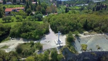 Büyük beyaz bir haç küçük bir kasabaya bakıyor. Doğa çok güzel ve yeşil görünüyor. Hava görüntüsü.