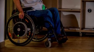 Tekerlekli sandalyedeki bir adam asansörden çıkıyor..