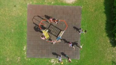 Çocuklar okulun dışındaki oyun bahçesinde oynuyorlar. Tırmanıyorlar ve sallanıyorlar..