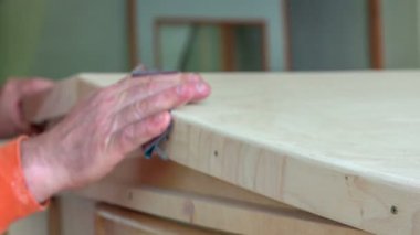 Orta yaşlı bir adam eski model bir arabanın çatısını öğütüyor. Sonra da eliyle yüzeye dokunuyor..