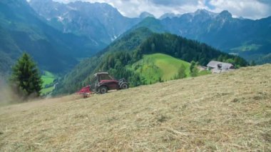 Sıcak bir yaz gününde bir çiftçi tarlada çalışıyor ve saman hazırlıyor. Arkasındaki manzara muhteşem..