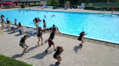 DOMZALE, SLOVENIA - 20. Haziran 2015 'te genç bir dansçı takımı bir yüzme havuzunun yanında hip hop koreografisi yapıyor. Sıcak bir yaz günü. Hava görüntüsü.