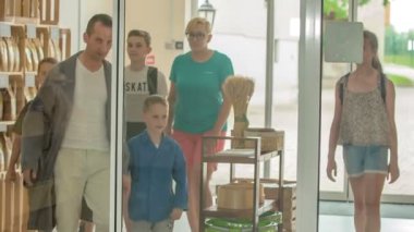 Heyecanlı okul çocukları büyük bir odaya giriyorlar ve bir rehber onlara ahşap değirmeni ve nasıl kullanıldığını gösteriyor..