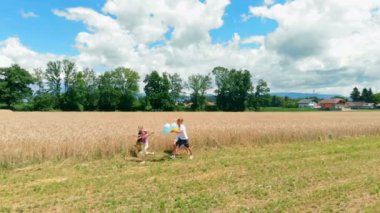 Genç bir aile tarlalarda yürüyor ve sonra koşmaya başlıyorlar. Bir kız farklı renkte balonlar taşıyor..
