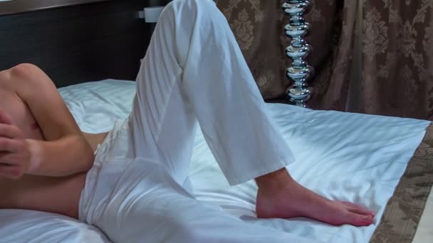 Sadece Beyaz Pantolonunu Giymiş Yatağa Uzanmış Genç Bir Adam Kameraya — Stok video