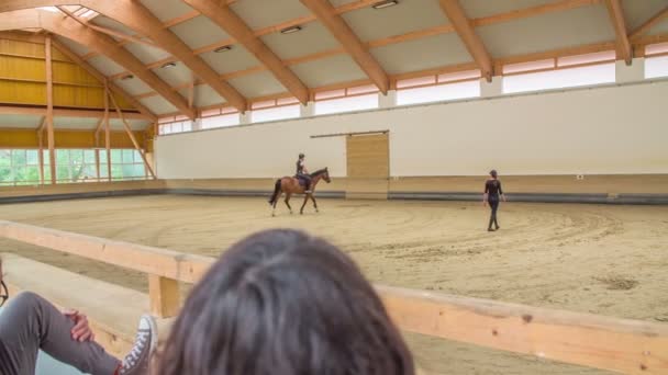 我们可以看到一个年轻姑娘骑着马在马场上 还有她的教练 这个女孩的家人在看着她 — 图库视频影像