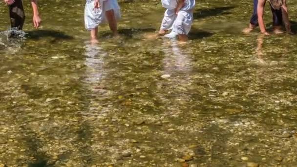 子供たちは服を着て水の中で楽しんでいます 水を撒き散らしてる — ストック動画