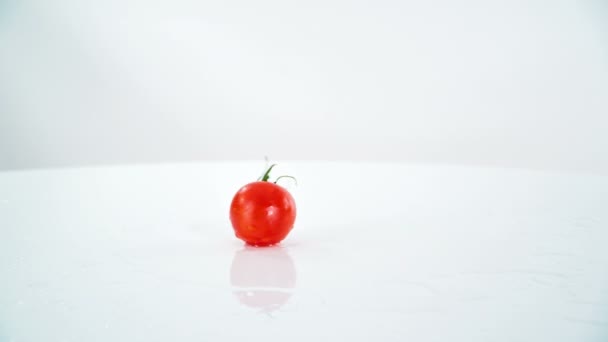 Eine Kleine Rote Tomate Fällt Auf Den Tisch Und Dreht — Stockvideo