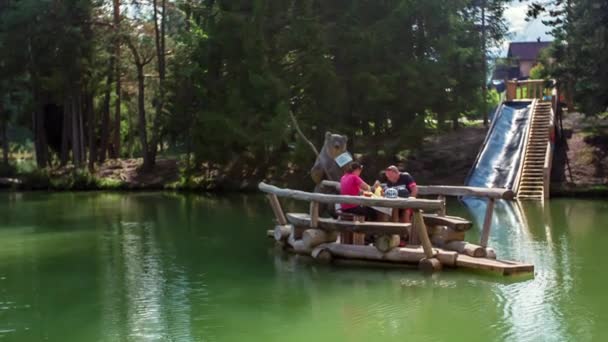 夫婦は川の真ん中で昼食を食べている 彼らはテーブルに座っていて テーブルはいかだに乗って川を泳いでいます — ストック動画